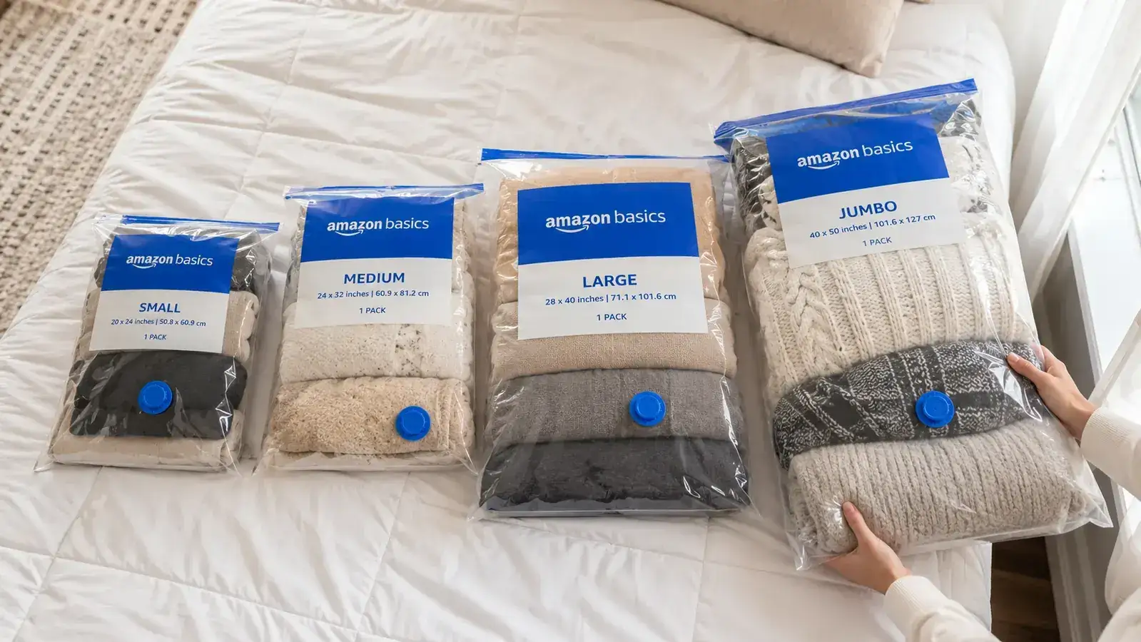 Vacuum storage bags in four sizes laid out side by side on a bed before being packed