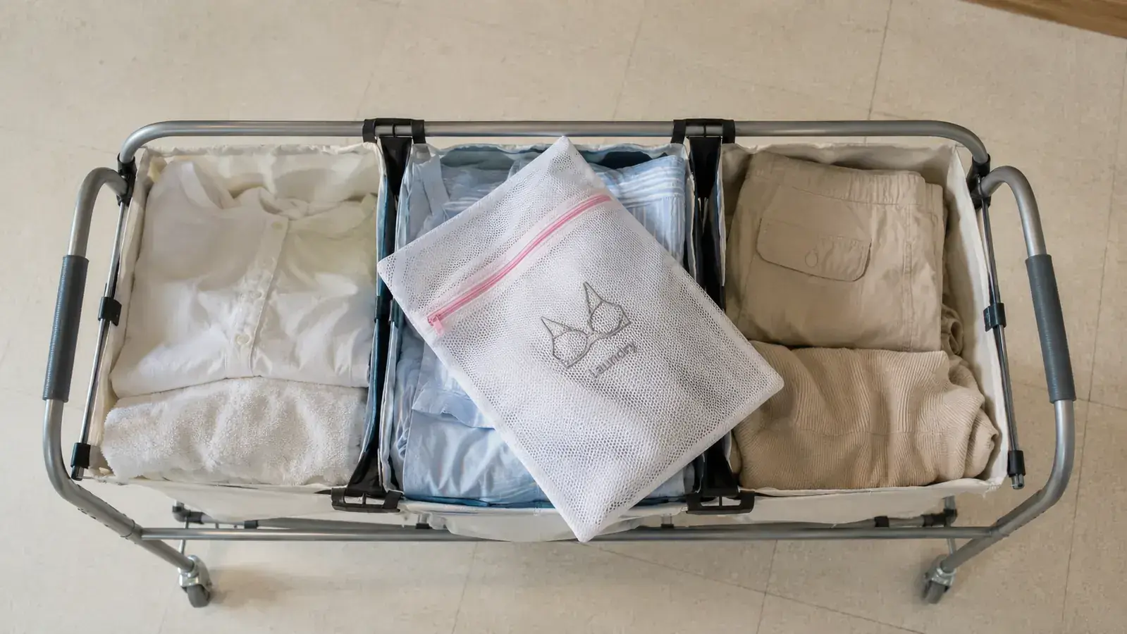 Overhead view of a laundry sorter cart with bags neatly loaded and a small mesh bag of delicates on top