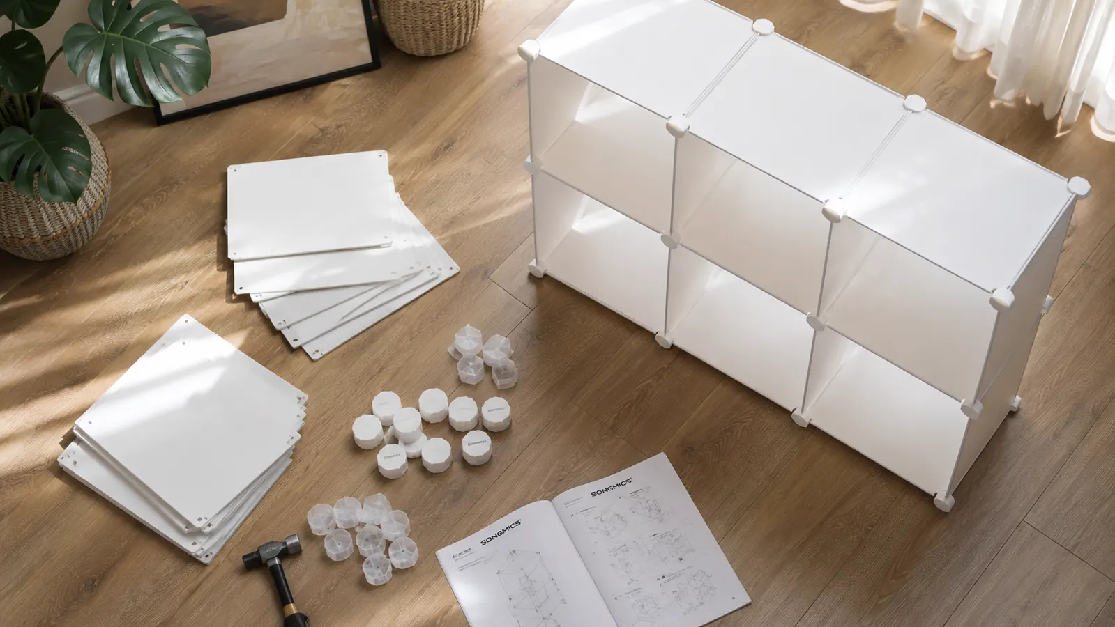 SONGMICS 6-cube storage organizer disassembled on a hardwood floor with panels and connector clips laid out for inspection
